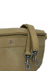 Borsa in pelle beige con chiusura a zip, caratterizzata da un emblema ad ancora in argento e doppi ganci metallici su una tracolla testurizzata.