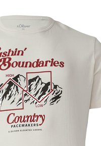 Biała bawełniana koszulka z czarnymi grafikami górskimi i napisem "Pushing Boundaries" na czerwono. Pod spodem znajduje się napis "Country Pacemakers" w czerwonym i czarnym kolorze.