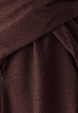 Tissu marron foncé avec une texture lisse, présentant des plis drapés et un poids légèrement plus lourd, indiquant un matériau doux et confortable.