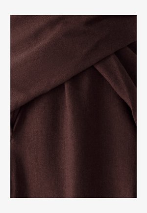 Tissu marron foncé avec une texture lisse, présentant des plis drapés et un poids légèrement plus lourd, indiquant un matériau doux et confortable.