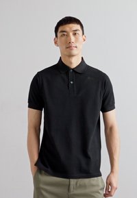 Sort polo skjorte med klassisk design. Korte ærmer, tre-knaps placket, lavet af blødt stof, der har en afslappet pasform og minimale detaljer.