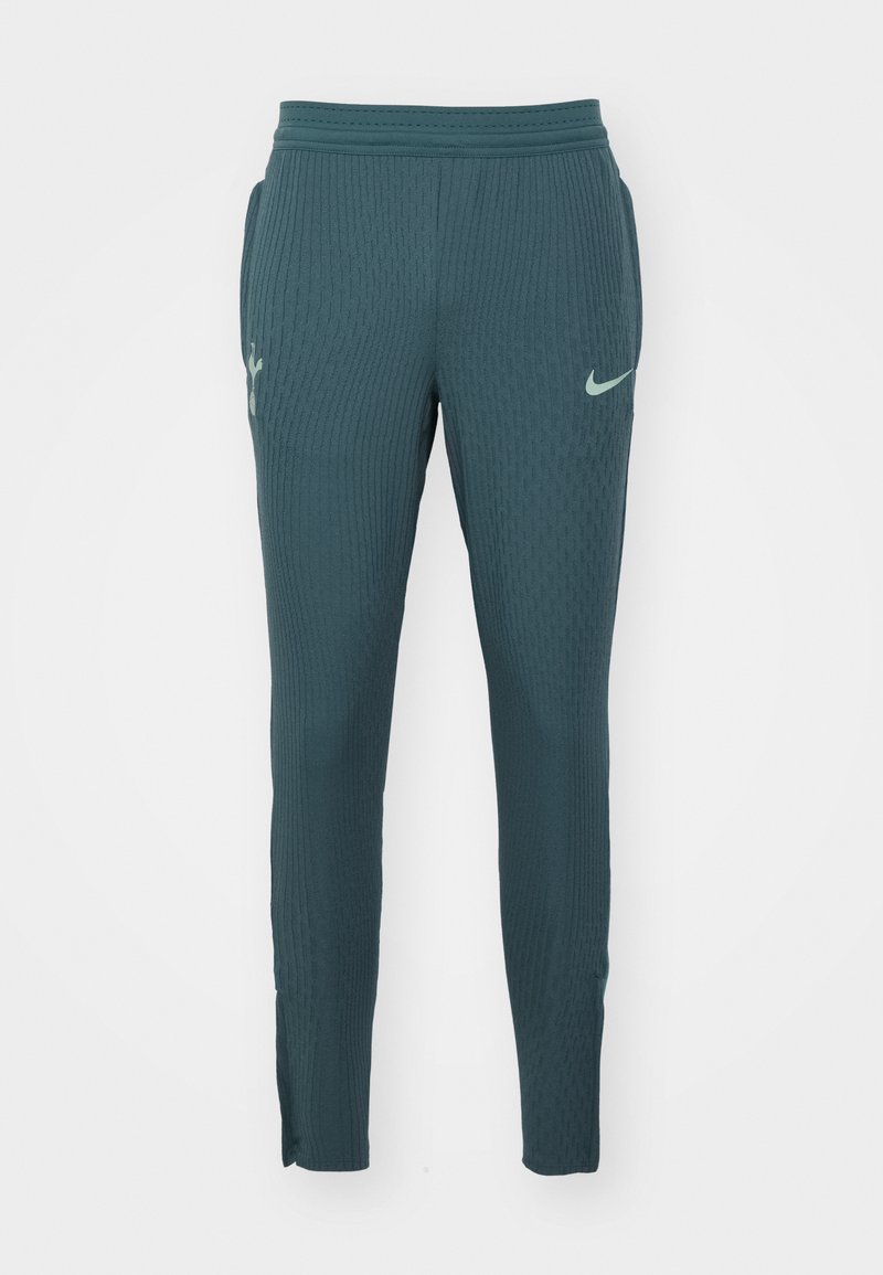 Pantalons de sport texturés teal avec un design côtelé, taille élastique et poches latérales. Présente un logo Nike vert clair sur le devant.