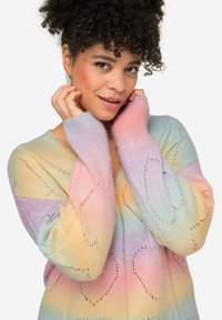 Cardigan lavorato a maglia con colori pastello arcobaleno, scollo a V, vestibilità ampia e motivi a cuore. I polsini a costine aggiungono texture e dettaglio.