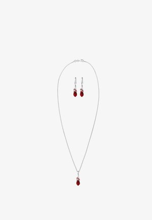 Collier pendentif en cristal rouge avec boucles d'oreilles pendantes assorties. Chaîne en ton argenté, présentant des formes en goutte d'eau et des accents métalliques.