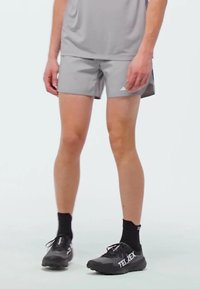 Gray athletic shorts made of lightweight fabric, paired with black socks and black TERREX shoes, showcasing a streamlined, minimalist design.