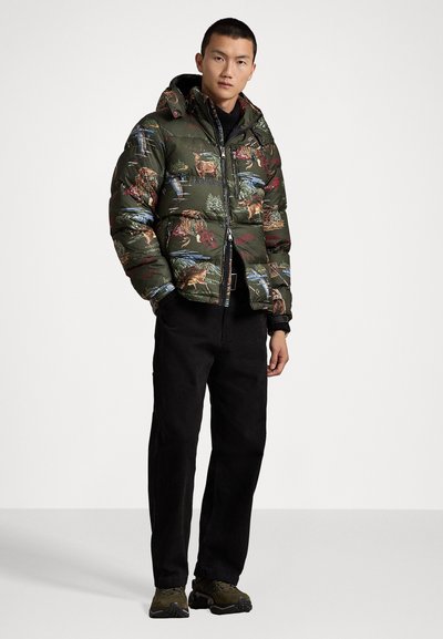 Puffer jacket in olive green with wildlife patterns, zip closure, adjustable hood, and ribbed cuffs. Paired with black pants and sneakers.