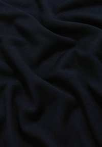 Tessuto di maglia blu navy scuro con pieghe morbide visibili e una fine texture a coste.