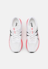 Vitaidid vit träningsskor med en lättmeshovandel, svarta accenter och en klar rosa sula. Har snörning och en vadderad krage för ökad komfort.