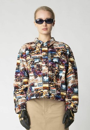 Collared, cropped jacket with a colorful, abstract cityscape print; features two front pockets and silver snap buttons. Black leather gloves.