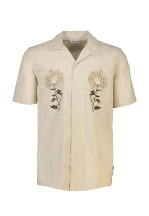 Kortærmet, lys beige skjorte med struktureret stof. Har broderede blomsterdesigns i gul og brun på forsiden, traditionel krave og knaplukning.