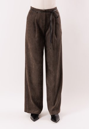 Pantaloni marroni a gamba larga in tessuto strutturato, con cintura a coulisse e pieghe frontali, abbinati a scarpe nere con punta a punta.