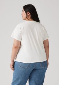 Λευκό βαμβακερό T-shirt με κοντά μανίκια, στρογγυλή λαιμόκοψη, απαλό ύφασμα, σε συνδυασμό με τζιν παντελόνι ανοιχτού μπλε χρώματος με πίσω τσέπες.