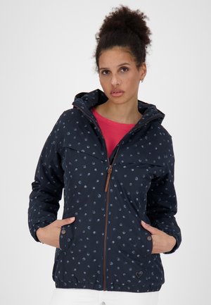 Marineblauwe jas met een capuchon, voorzien van lichtblauwe stippen, een bruine rits en elastische manchetten. Twee voorzakken met subtiele branding.