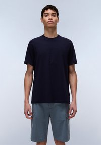 Navy blue cotton t-shirt featuring raised lettering, crew neck, and short sleeves, paired with light grey cargo shorts.
