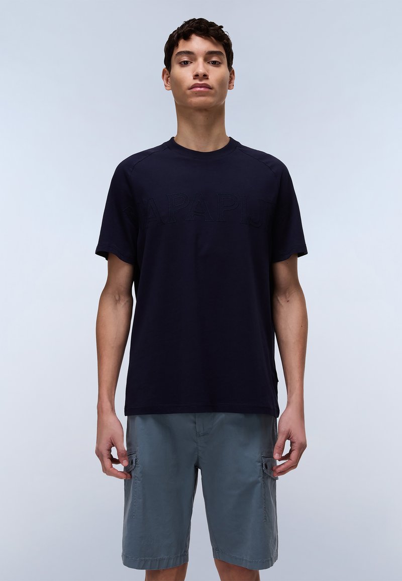 Navy blue cotton t-shirt featuring raised lettering, crew neck, and short sleeves, paired with light grey cargo shorts.