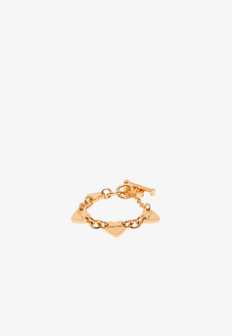 Pulsera en tono dorado con eslabones en forma de corazón y cierre de tipo toggle. Los eslabones tienen un detalle grabado, mostrando un acabado suave y brillante.