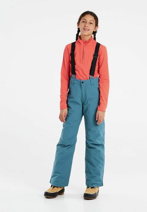 Turquoise sneeuwbroek met verstelbare zwarte bretels, gecombineerd met een nauwsluitend koraalkleurig shirt met lange mouwen. De broek heeft een recht model.