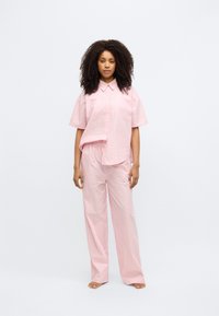 Ροζ και λευκό ριγέ πουκάμισο με κοντό μανίκι και γιακά, συνδυασμένο με παντελόνι με ελαστική μέση στο ίδιο σχέδιο. Λείο ύφασμα, άνετη εφαρμογή.