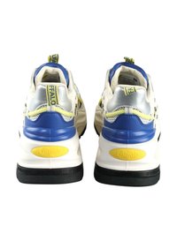 Fehér sportcipők kék, sárga és ezüst részletekkel. Vastag fekete gumi talp. A hátsó részen egy sárga logó és egy kék húzófüle található.