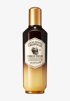 Flacon de Skinfood Royal Honey Propolis Enrich Toner avec bouchon doré et dégradé ambre foncé à clair, étiquette montrant un pot de miel et une abeille.