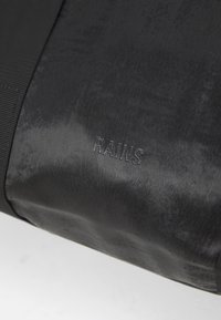 Svart vanntett veske laget av glatt, matt materiale. Med preget "RAINS"-logo og teksturerte stripe detaljer. Kompakt og minimalistisk design.