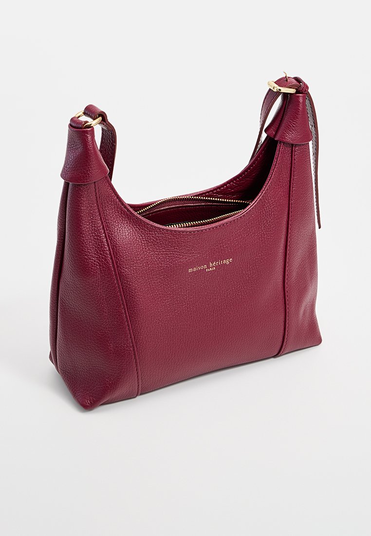Sac à épaule en cuir granulaire rouge foncé avec fermeture éclair dorée, bandoulière ajustable et logo doré embossé "maison héritage Paris" à l'avant.
