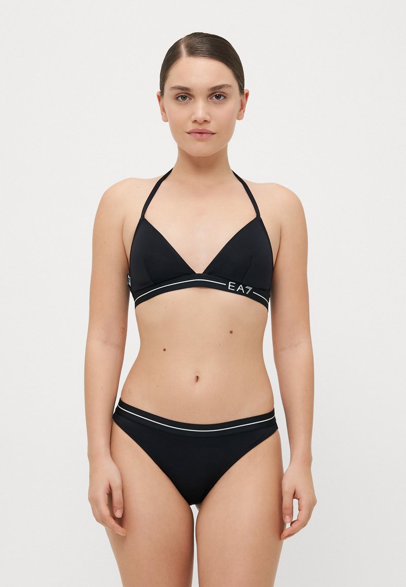 Melna bikini ar trīsstūra augšdaļu un biksītēm, kas rotāta ar kontrastējošu baltu joslu ar "EA7" logo priekšpusē. Gluda tekstūra, minimāls dizains.