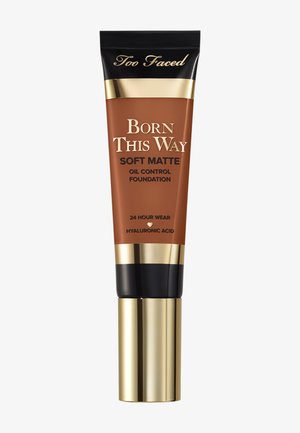 Too Faced Born This Way Soft Matte Foundation tube, bruine tint, met gouden en zwarte accenten, voorzien van oliecontrole en hyaluronzuur.