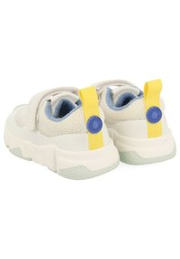 Zapatillas de malla blancas con un forro en azul claro, una pestaña amarilla y una suela texturizada. Cuenta con tiras de Velcro para poner y quitar fácilmente.