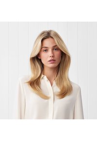 Camicia button-up color crema con colletto, realizzata in materiale morbido simile alla seta e con maniche lunghe e ampie, presentata su uno sfondo bianco semplice.