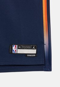 Košarkarska majica mornarske barve z zračnim materialom in oranžnimi gradientnimi poudarki. Oznake vključujejo NBA, Jordan in velikost XL, kar potrjuje avtentičnost.