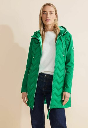 Grön, vadderad jacka med zigzag-mönster, som har huva och kontrasterande ljusblå innerfoder. Dragkedja framtill och sidofickor.