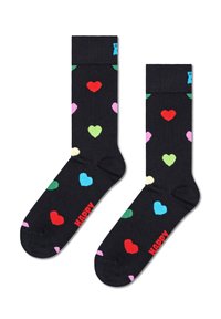 Chaussettes noires avec des motifs de cœurs colorés en rouge, rose, vert, bleu et jaune. Présentent un texte "HAPPY" rouge à la cheville. Tissu doux.