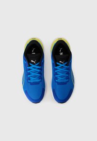 Une paire de chaussures de course Puma bleues avec des languettes noires, des lacets bleus et des accents jaunes, vue de dessus sur un fond blanc.