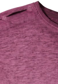 Gros plan sur un tissu chiné violet montrant le col rond et les coutures d'épaule sur un t-shirt à texture douce.