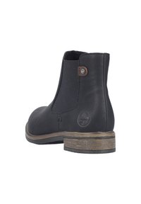 Bottines en cuir noir avec des panneaux latéraux élastiques, un talon plat et un détail logo. La semelle extérieure présente un aspect bois brun texturé.
