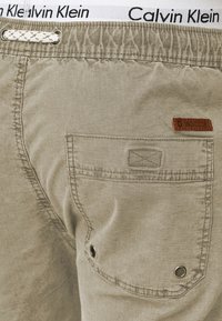 Beige shorts met een gestructureerde stof, een achterzak met een gestikt patroon en een Calvin Klein tailleband met geweven accenten.