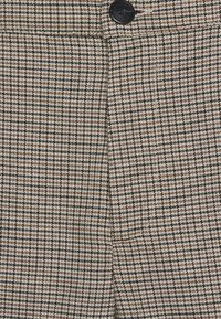 Bruin en beige houthakpatroon stof met een gladde textuur, met een zwarte knoopdetail in de taille.