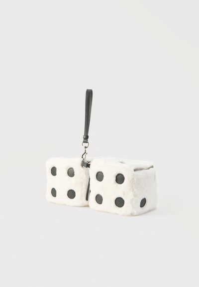 Δύο λευκοί χνουδωτοί ζαριές με μαύρες κουκκίδες, συνδεδεμένες με μεταλλικό κλιπ και προσαρμοσμένες σε μαύρο λουράκι καρπού σε λευκό φόντο.