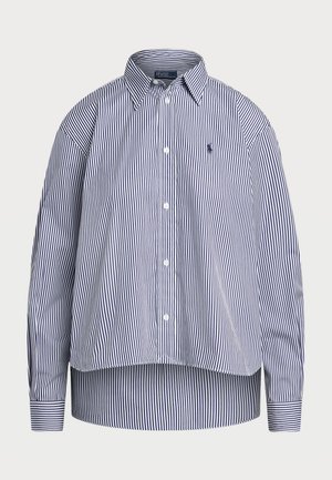 Striped button-up shirt in navy and white. Features a collar, long sleeves, and a slightly cropped back. Made of woven fabric.