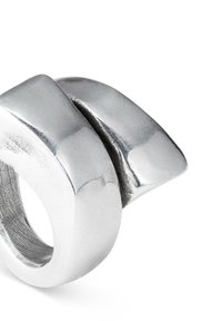 Anillo geométrico de plata con dos formas entrelazadas, acabado pulido, textura suave y un diseño ligeramente cónico.