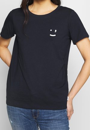 T-shirt en coton bleu marine à manches courtes, avec un petit graphique de smiley blanc sur la poitrine. Texture lisse, design à col rond.