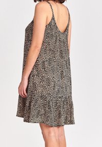 Robe à imprimé léopard avec fines bretelles, dos échancré et ourlet évasé. Confectionnée en tissu léger pour une coupe décontractée.