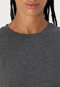 Maglietta grigia a maniche corte con colletto girocollo, dal design aderente e con una consistenza morbida, dotata di dettagli sottili attorno al collo, adatta per un abbigliamento casual.