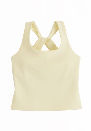 Haut court sans manches jaune pâle avec des larges bretelles croisées dans le dos et un ourlet droit.