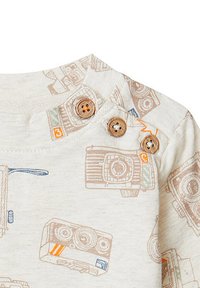 Hellbeige Kurzarmhemd mit einem Kamera-Print in Braun und Blau. Drei Holzknöpfe an der Schulter erleichtern das An- und Ausziehen.