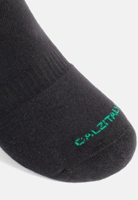 Calcetín negro con una textura suave, con una parte superior acanalada y puntera reforzada. "CALZITALY" impreso en verde en el área de la puntera.