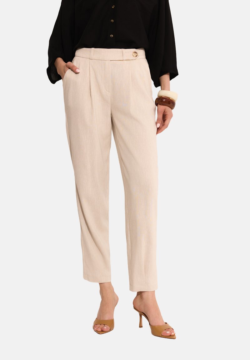 Beżowe spodnie o prostym kroju z fałdami z przodu i detalem guzika z boku. Wykonane z teksturowanej tkaniny, z ukośnymi kieszeniami.