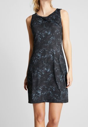 Robe noire sans manches à motif marbré bleu portée par une personne debout devant un fond gris uni.