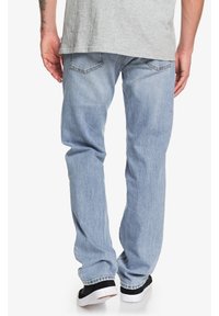 Ljusblå denimjeans med avslappnad passform, med femficksdesign och subtila blekningar. Bärs med svarta sneakers.